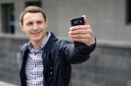 Young man making selfie with his phone on the streetの写真素材