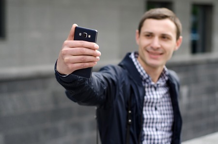 Young man making selfie with his phone on the streetの写真素材