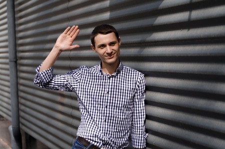 Young man says hello to friend on the streetの写真素材