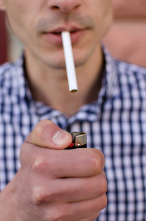 Young man smoking cigarette on the streetの写真素材