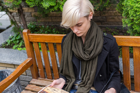 Young woman reading magazine on the bench in the cityの写真素材