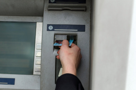 Young blonde woman using cash machine on the streetの写真素材