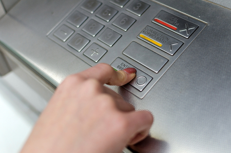 Young blonde woman using cash machine on the street