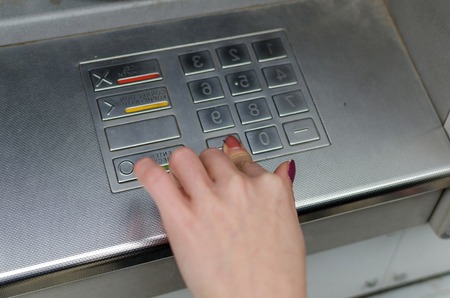 Young blonde woman using cash machine on the streetの写真素材