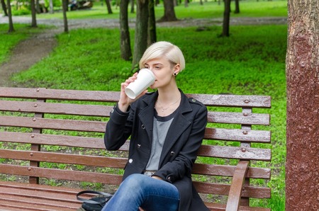 Young girl with a plastic cup of coffee walking on the cit streetsの写真素材