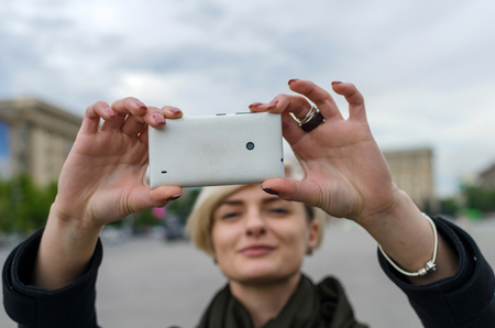 Young blonde girl making selfie in the cityの写真素材