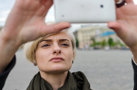 Young blonde girl making selfie in the city