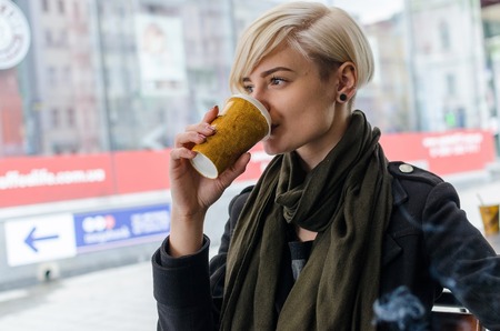 Young girl with a plastic cup of coffee walking on the cit streetsの写真素材