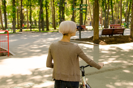 Young beautiful girl riding a white bicycle in the parkの写真素材