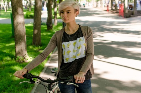 Young beautiful girl riding a white bicycle in the parkの写真素材