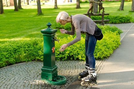 Young girl with black rollers in the park washing her hands