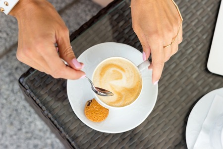 Young woman drinking coffe in the cafe onteh streetの写真素材