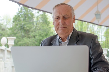 Aged man is using laptop in the parkの写真素材
