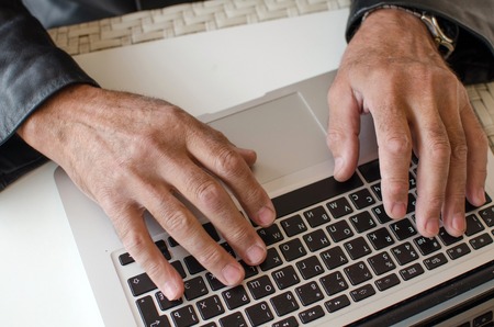 Aged man is using laptop in the park