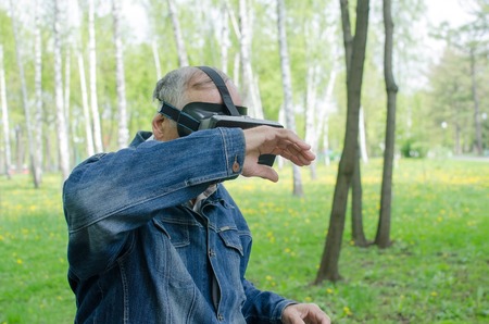 Aged man is using virtual glasses in the park