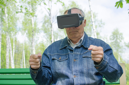 Aged man is using virtual glasses in the parkの写真素材