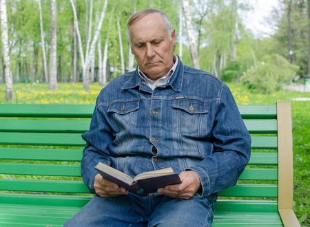 Aged man is reding the book in the parkの写真素材