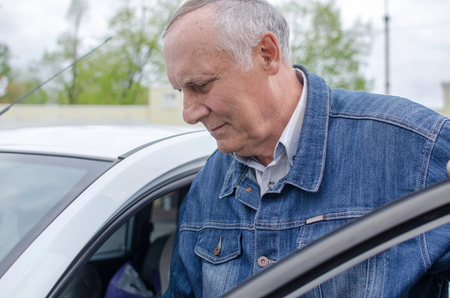Aged man is sitting in the car