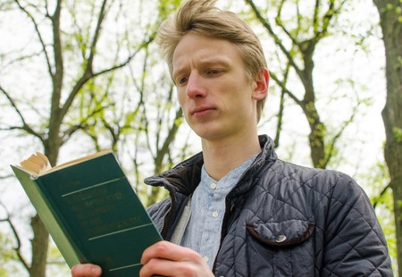 Young man reading a book in the parkの写真素材