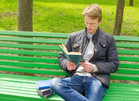 Young man reading a book in the parkの写真素材