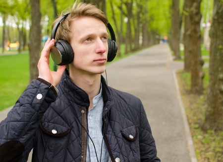 Young man listening to music in the headphones in the parkの写真素材