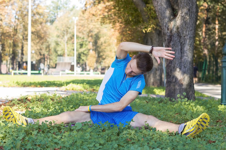 Young man making exersises in the park in the matの写真素材