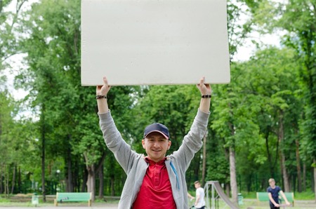 Man with white billboard in park natureの写真素材