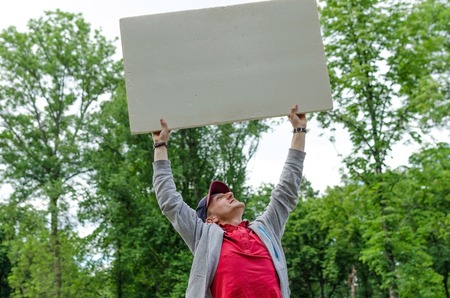 Man with white billboard in park natureの写真素材