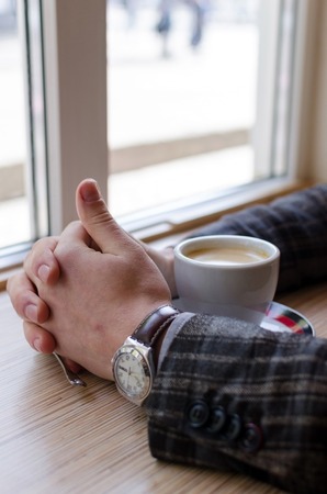 Close-up photo of the cup of latte and man hands with watchの写真素材