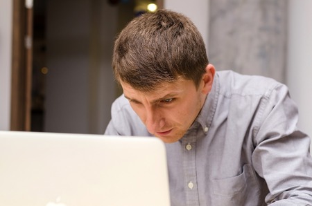 Close-up photo of young man tilting his head to laptopの写真素材