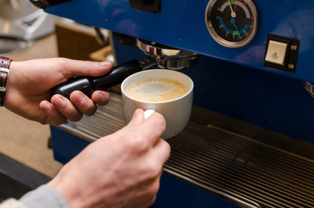 Close-up photo of ready cup of coffee and coffee machineの写真素材