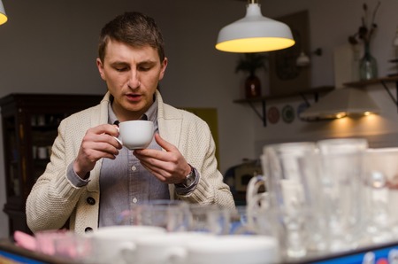 Young man blowing on his coffee to make it coolerの写真素材