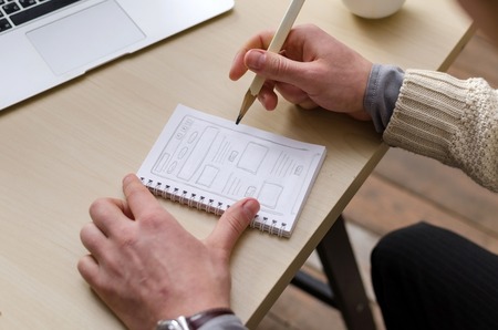 Young man drawing smth on little paper
