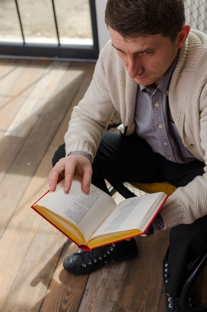 Young man is reading book seating on the chairの写真素材
