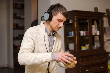 Young man in headphones holding a glass bowlの写真素材
