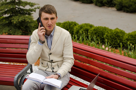 Young man is talking on the phone in a parkの写真素材
