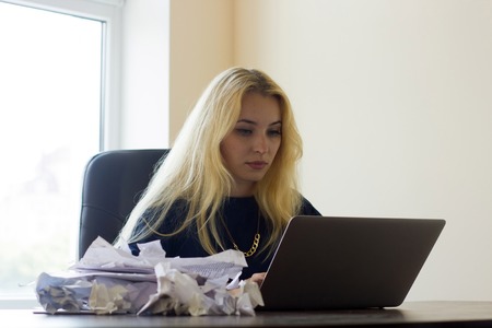 Young woman in the office with the pile of documents