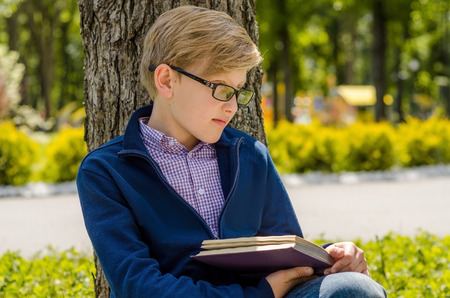 Teenager is reading a book in the park