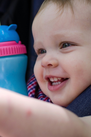 Small baby boy is drinking from the colorful bottleの写真素材