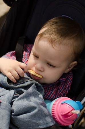 Small baby boy is eating in the parkの写真素材