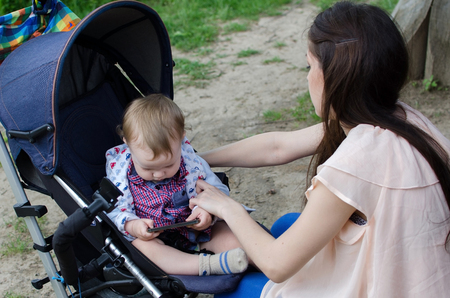 Young mother is walking with her small child in the parkの写真素材