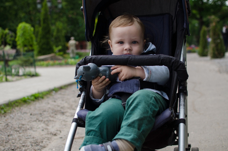 Small baby boy in the carriage in the parkの写真素材