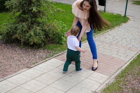 Young mother is walking with her small child in the parkの写真素材