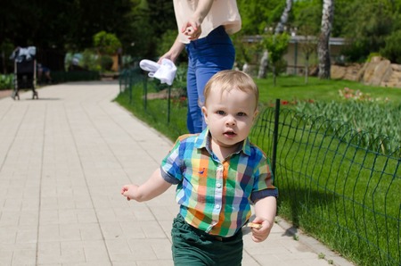 Young mother is walking with her small child in the parkの写真素材