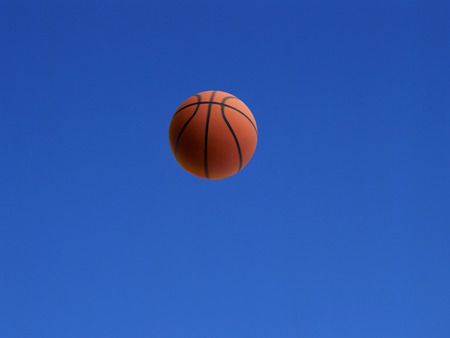 A basketball shot in the air with blue sky backgroundの写真素材