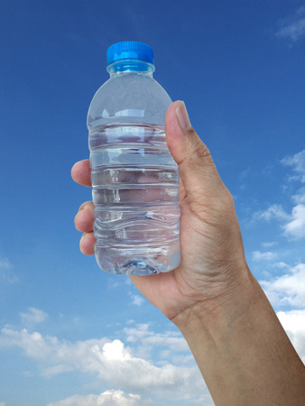 Hand holding water bottle isolated on sky backgroundの写真素材