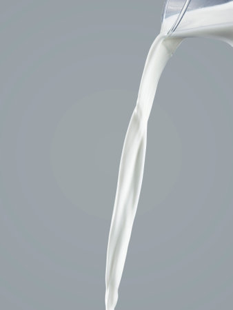 flowing milk from jug isolated on a gray backgroundの写真素材