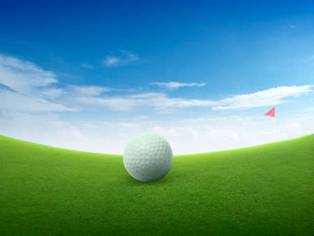 Close up golf ball on green grass field and red golf flag on green fairway with beautiful blue skyの写真素材