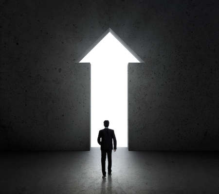 Businessman standing in front of bright big shining door arrowの写真素材