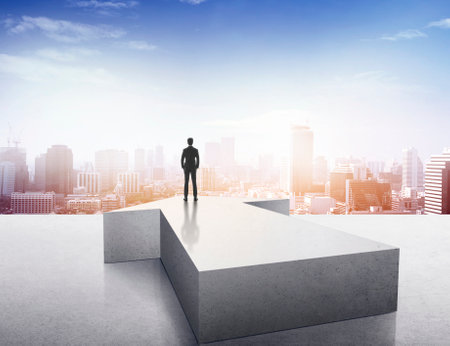 Vision concept. Successful businessman standing on arrow and looking over cityの写真素材